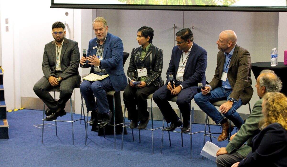 Hydrogen Summit 2025_024 A panel of five people (four men and one woman) are seated on high chairs on a low stage, participating in a discussion. They are all formally dressed, and microphones are visible