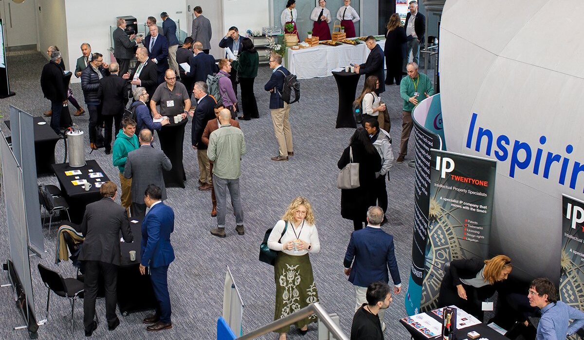 pic 1 CEME_Hydrogen_2025-135 Overview of a large, modern indoor venue for the Hydrogen Summit. Attendees network around tables near a large, central, egg-shaped structure with the text, "Inspiring. Inclusive. Innovative. Open and Honest." The image is taken from an upper level looking down wooden stairs.