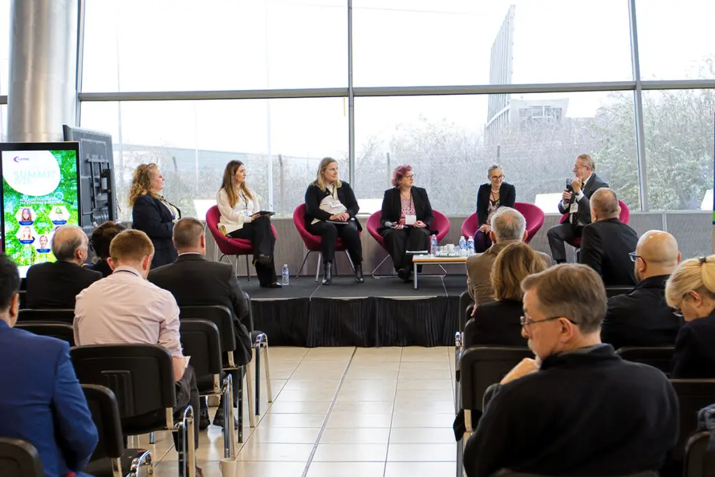 A panel discussion takes place in a large glass walled atrium.