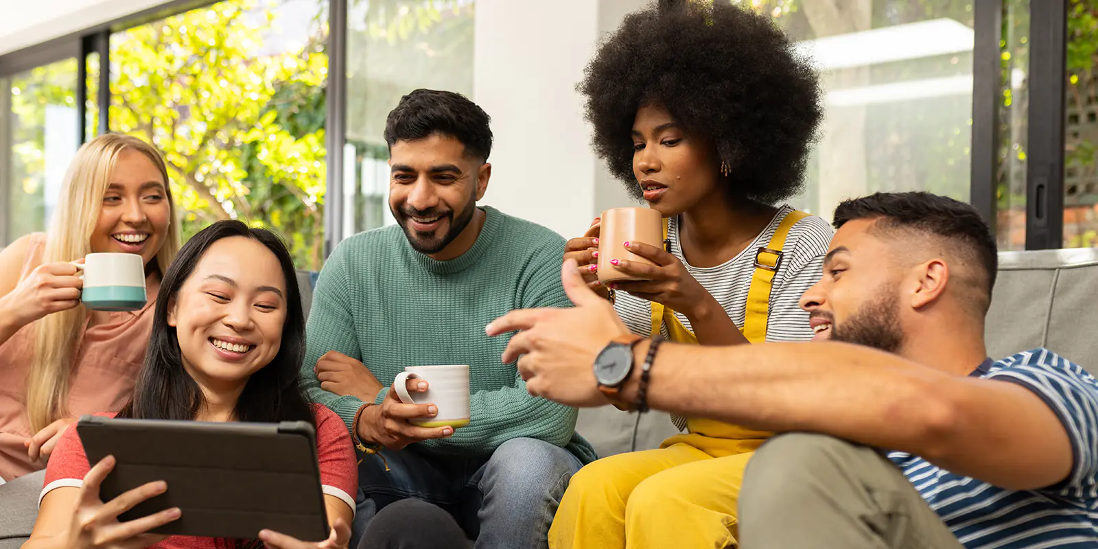 A group of five people discuss an idea over coffee in an informal setting.